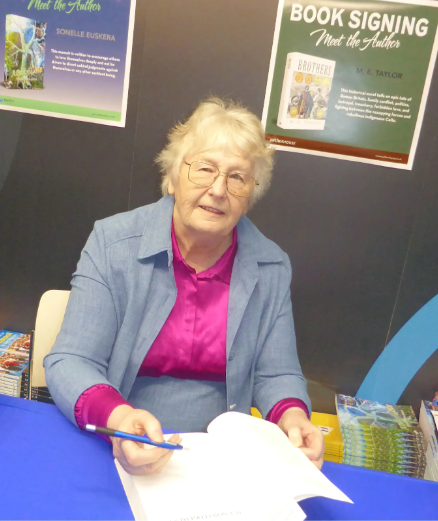Signing copies of Brothers at Mind Body and Spirit Festival at Olympia London 2025 (Image and caption credits: M. E. Taylor)